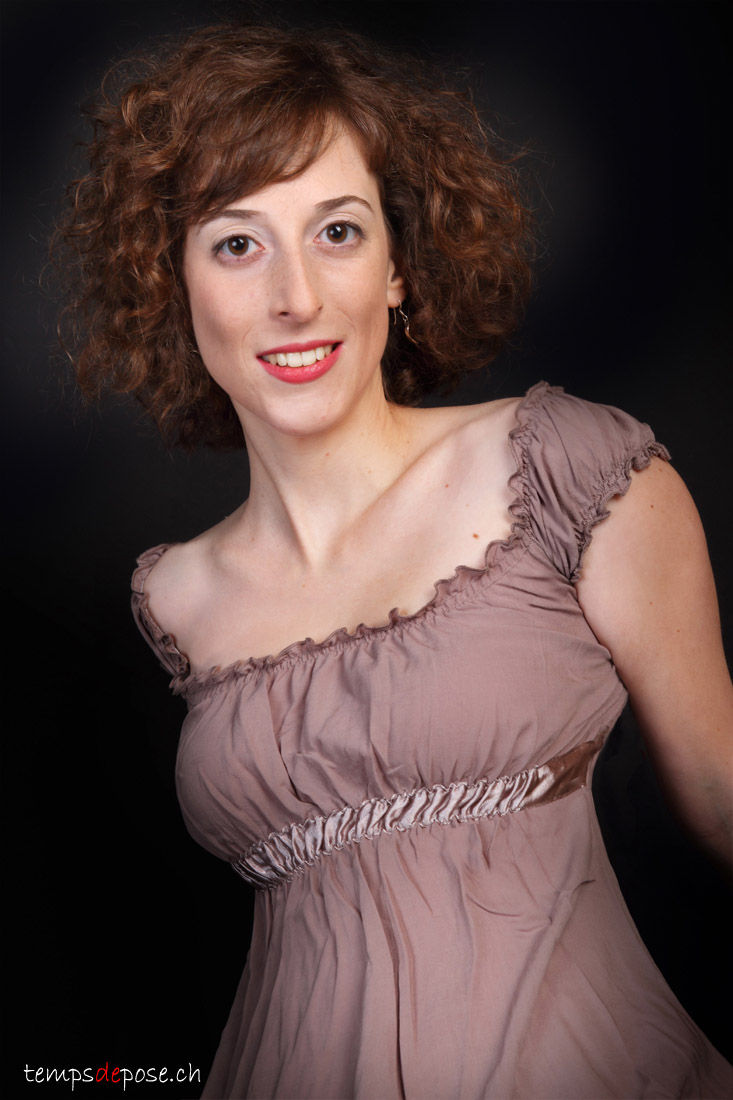 Portrait d'une jeune femme rousse au sourire charmeur.